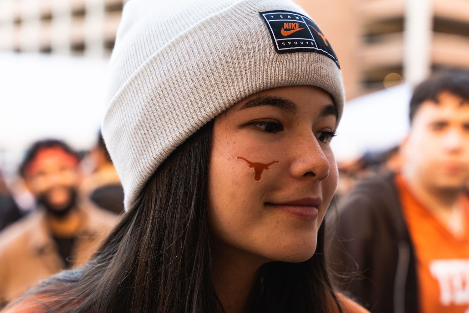 College sports fan wearing a beanie with a Longhorns logo at an outdoor event.