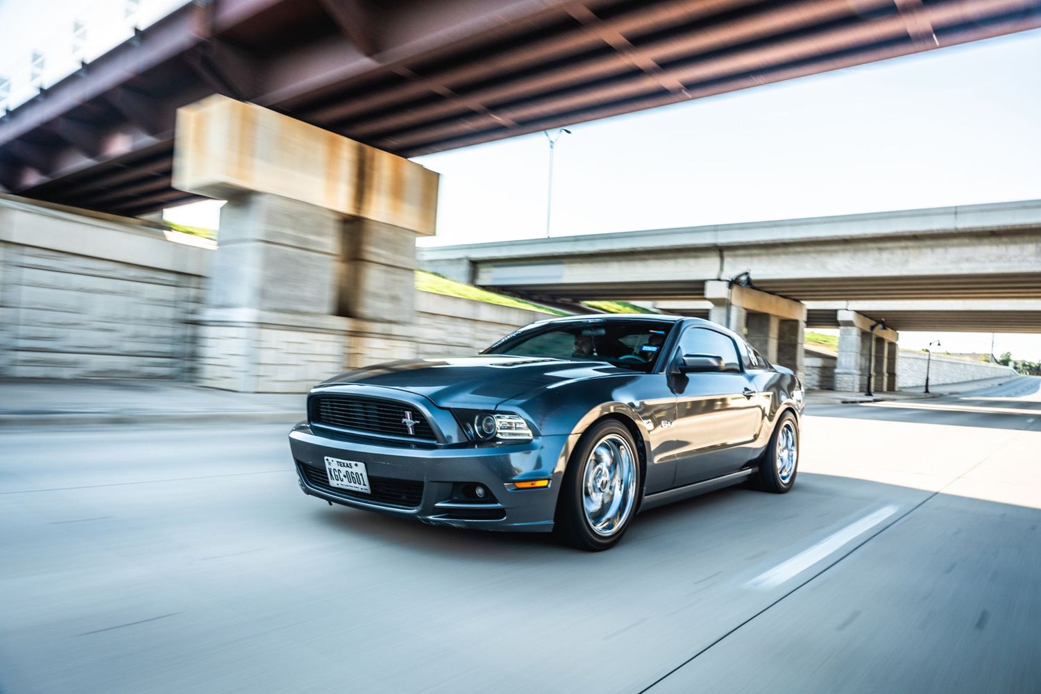 Ford Mustang GT speeding under bridge with dynamic motion blur effect.
