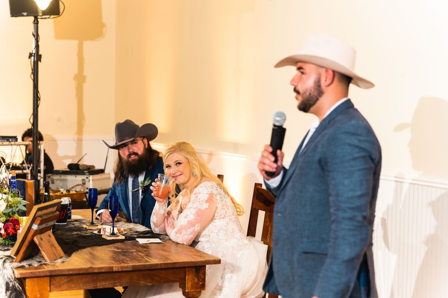 Wedding reception speakers sharing toasts and stories at the head table.