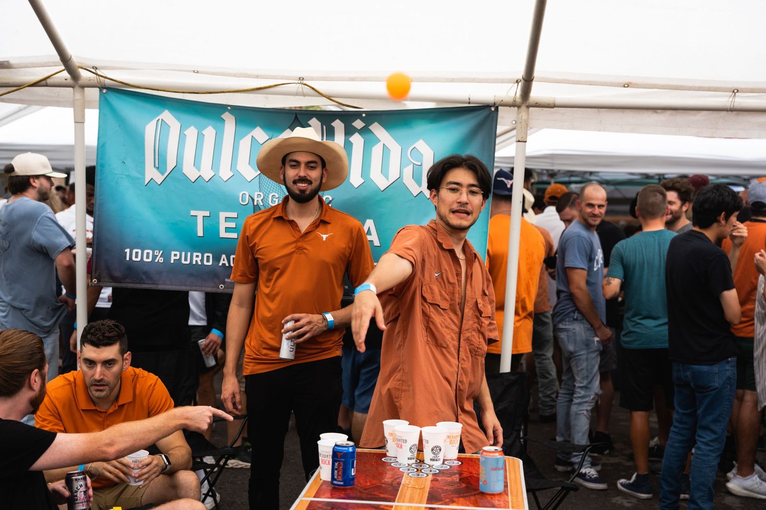 Vendors standing behind a drink table at an outdoor event with a Dulce Vida tequila banner.
