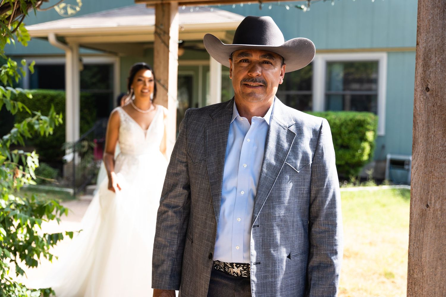 A western-style wedding photo featuring formal attire and a cowboy hat.
