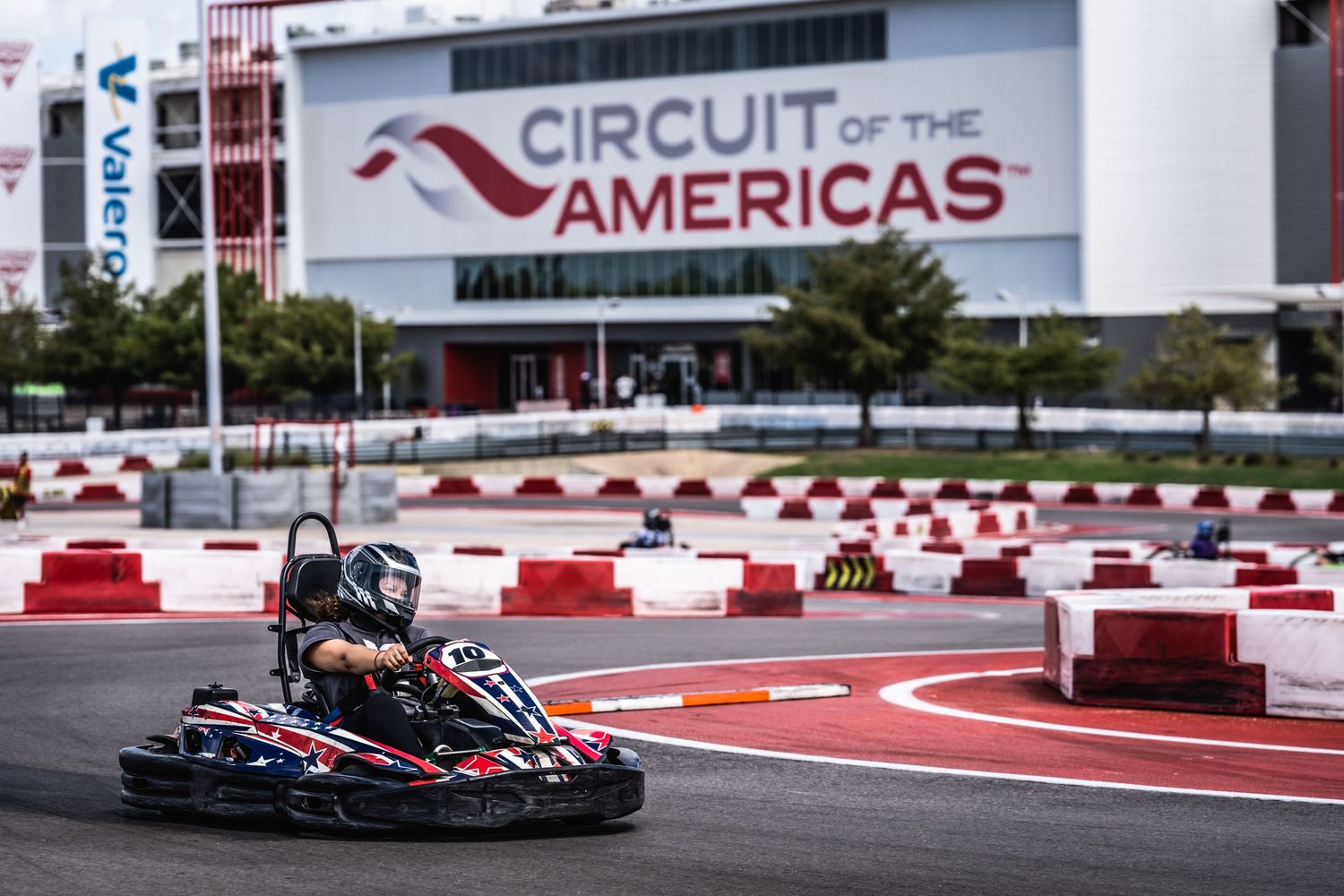 Go-kart racing at Circuit of the Americas with facility signage visible in background.