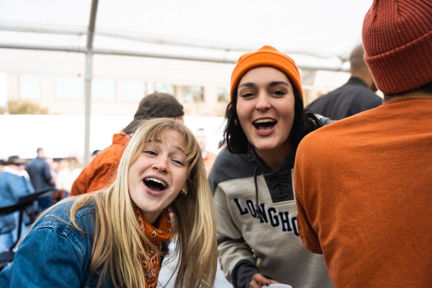 Friends showing excitement and joy while attending an outdoor campus celebration.