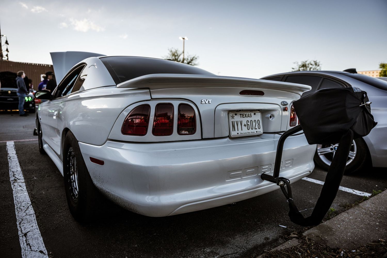 Rear view of a white Ford Mustang with distinctive taillights parked in a lot.