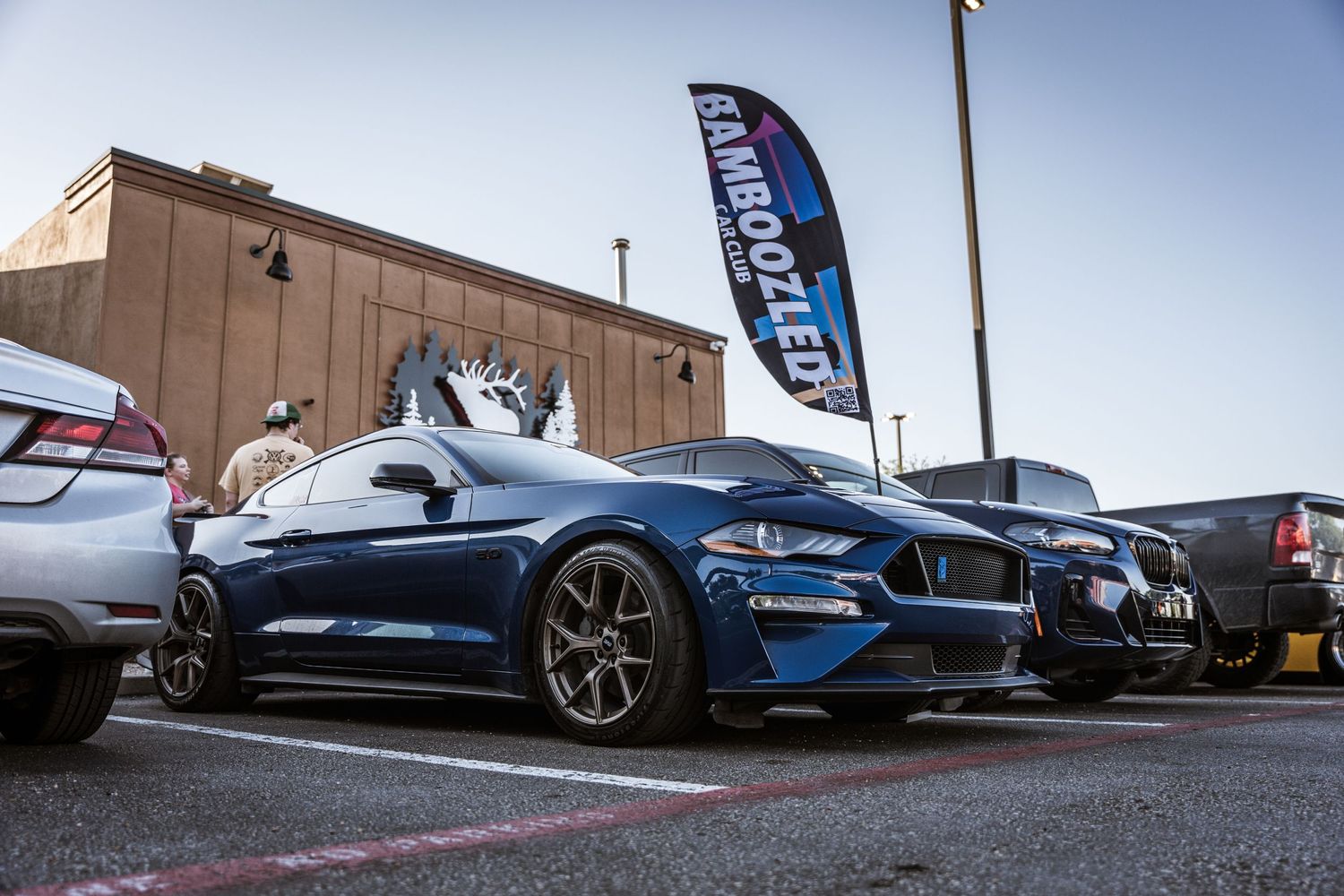 Blue Ford Mustang sports car parked at an automotive event with custom wheels and modifications.