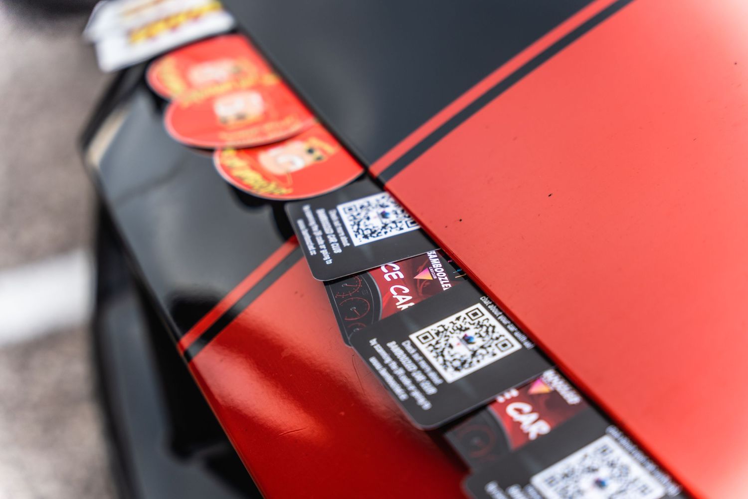 Close-up of performance modification stickers aligned on a red car's body panel.