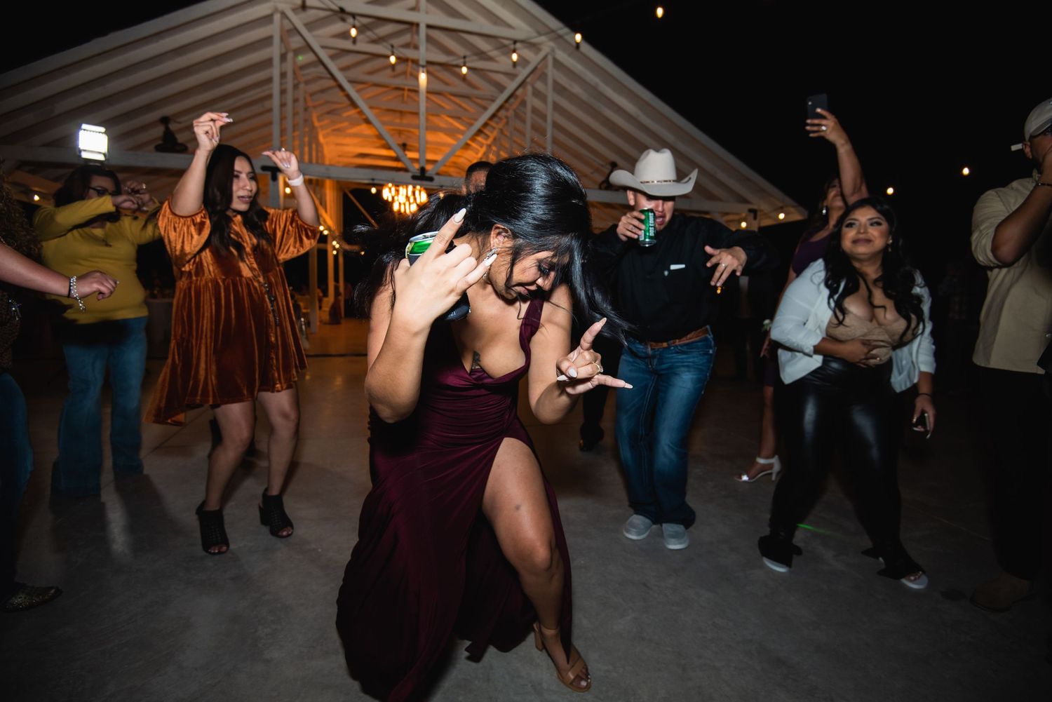 Wedding guests dance energetically on the dance floor at an indoor reception.