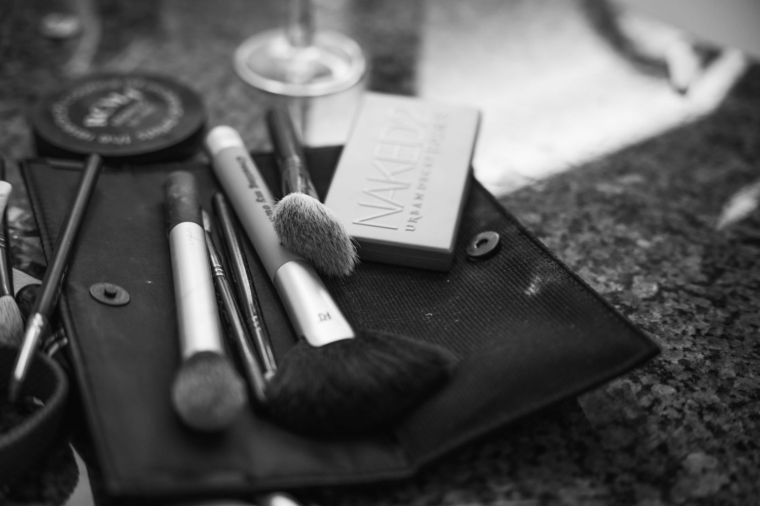 Close-up of makeup brushes and cosmetic products on dark surface in monochrome.