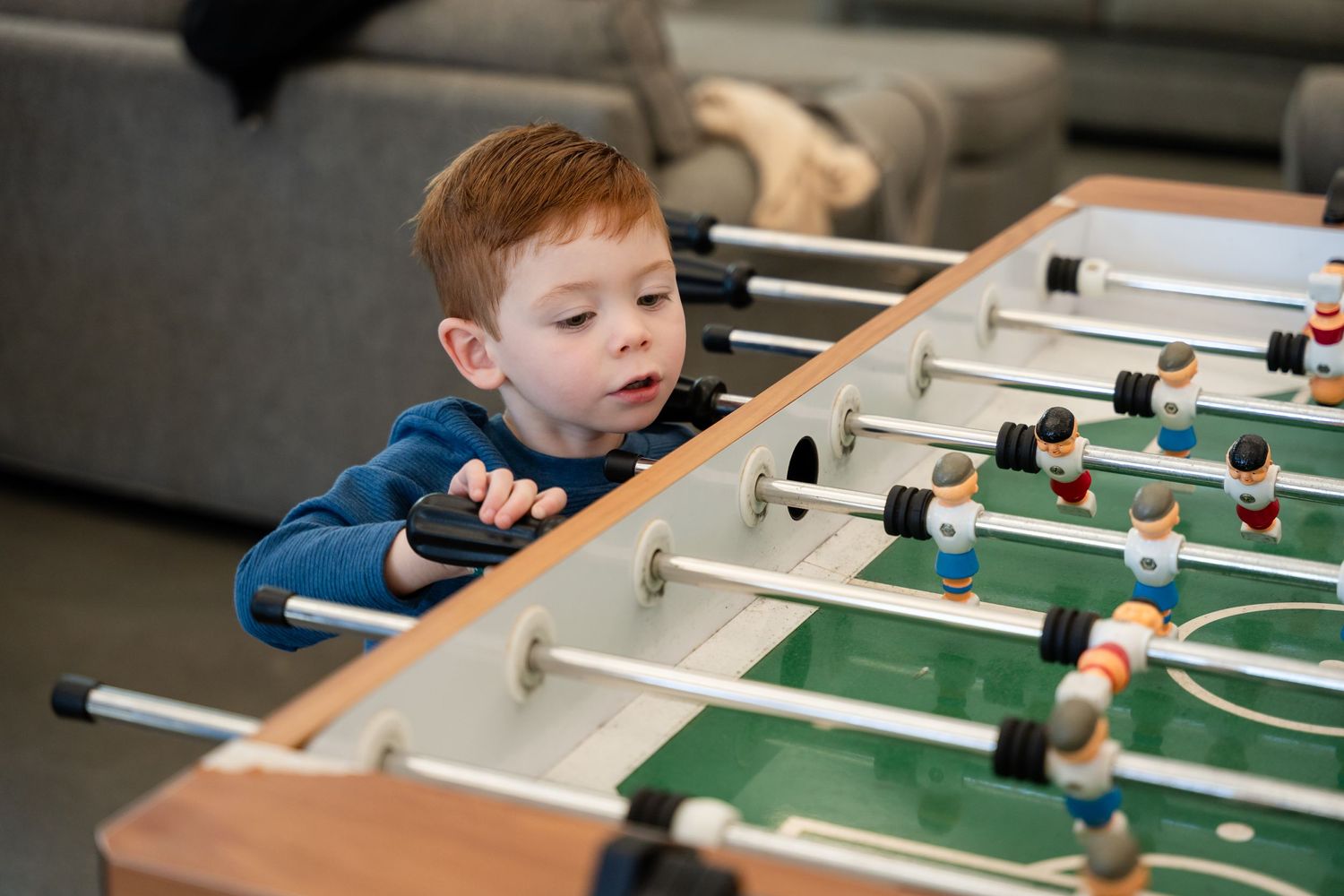 Young child playing table football in living room setting.