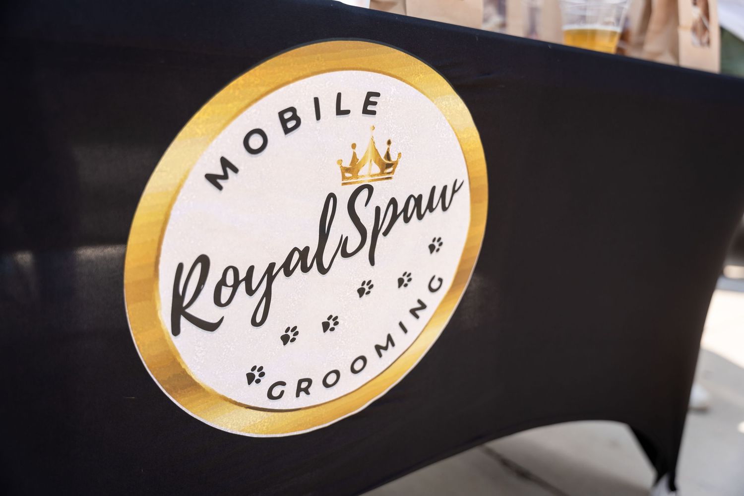 Close-up of a circular Royal Spawn mobile grooming logo in black and gold.