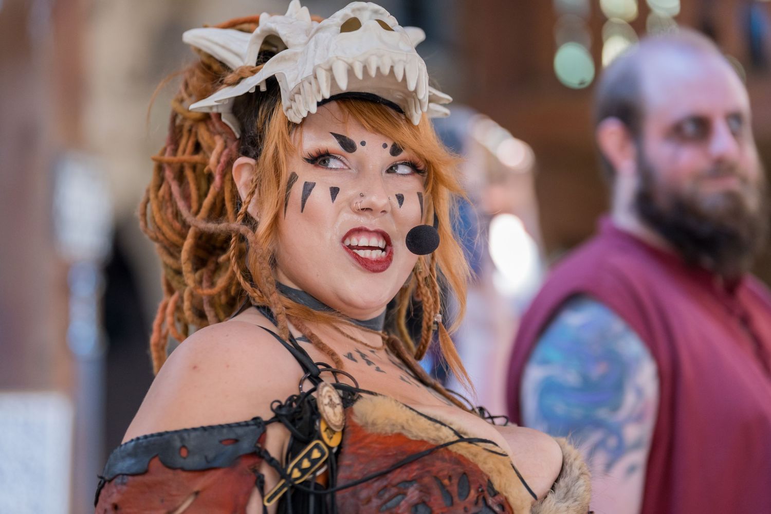 A performer in steampunk costume with leather and feathers poses at a renaissance fair.