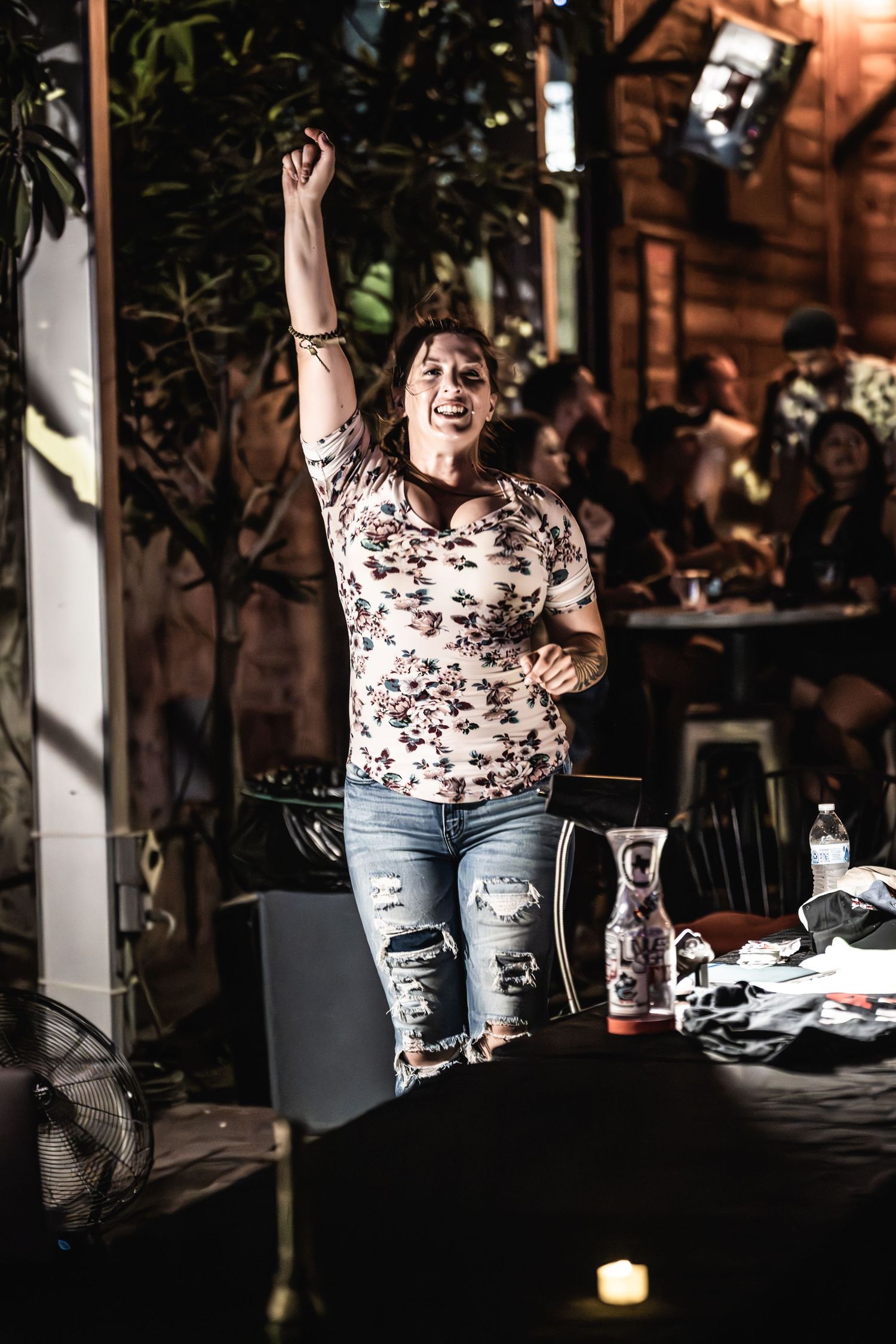 Concert performer raises arm enthusiastically while entertaining crowd on outdoor stage.