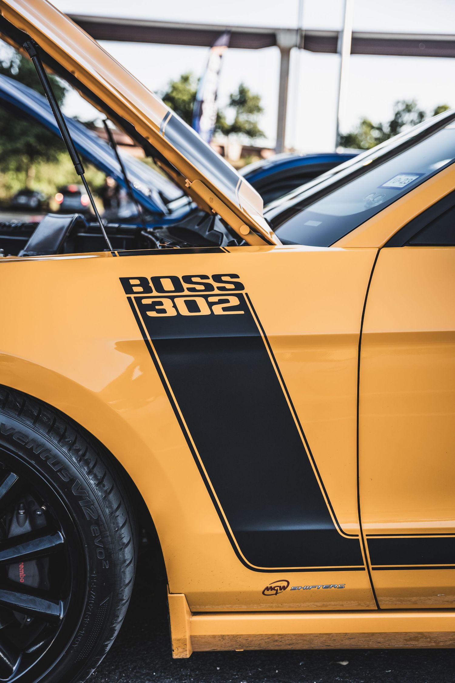 Yellow Mustang Boss 302 with black racing stripe detail shown from the side.