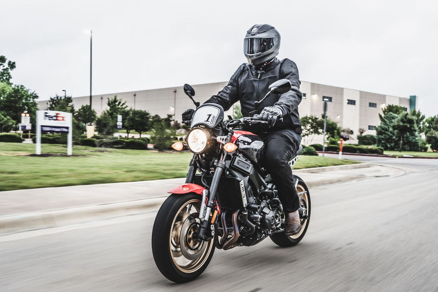 Motorcyclist in full gear riding red sport bike on urban street.