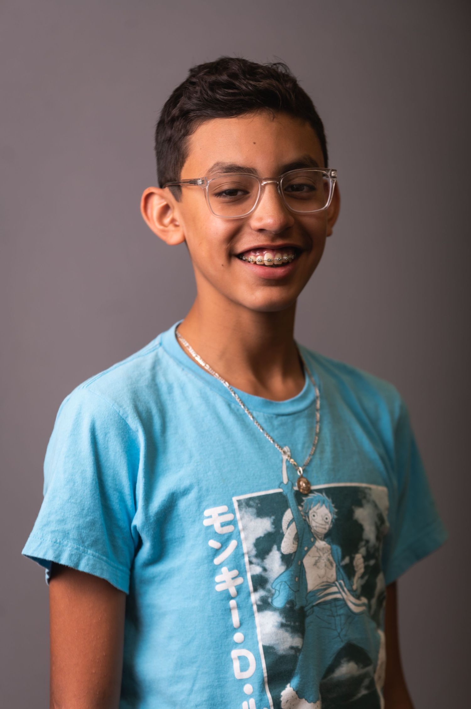 Studio portrait of young person in blue graphic t-shirt and glasses.
