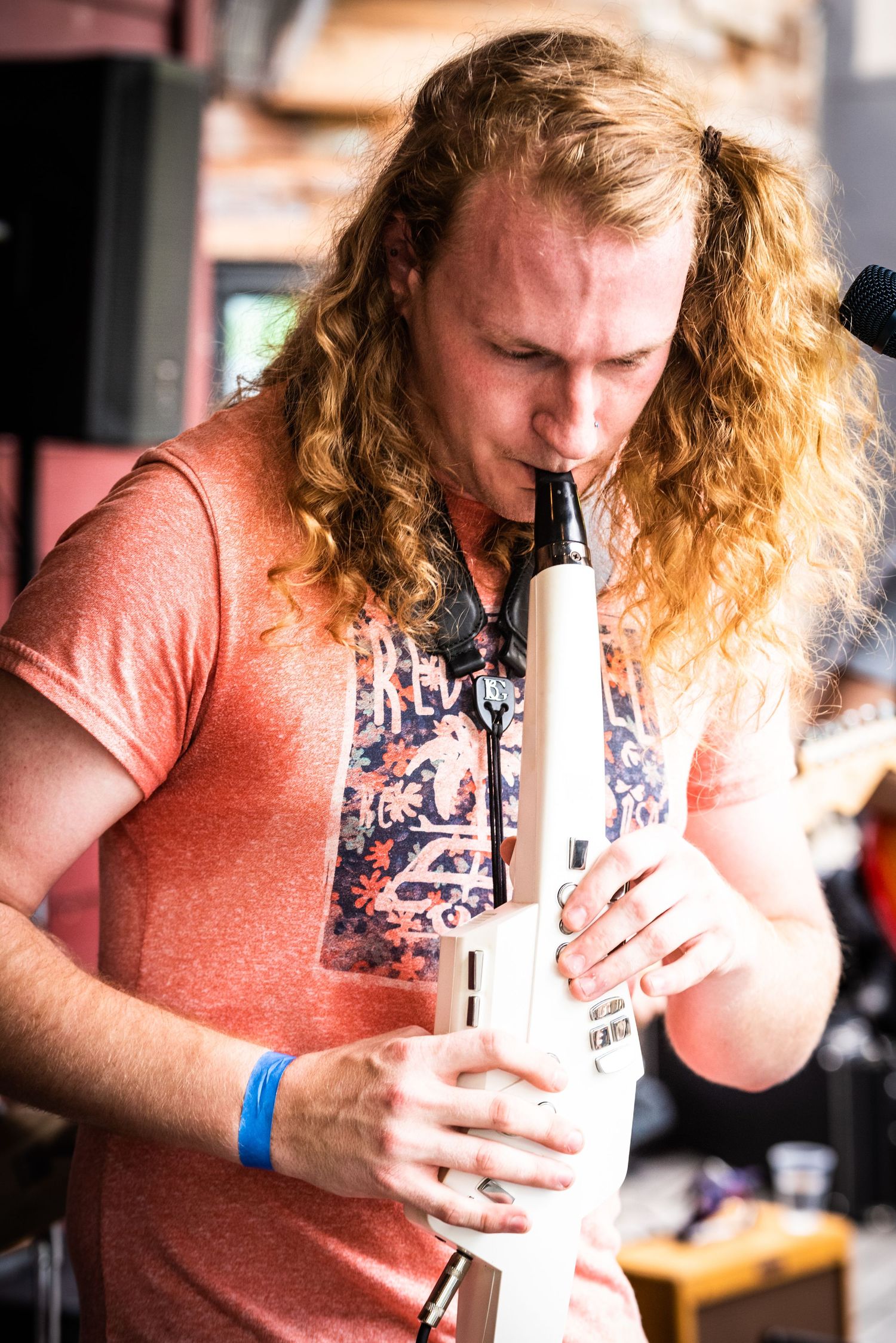 Musician playing a white wind instrument during an outdoor performance.