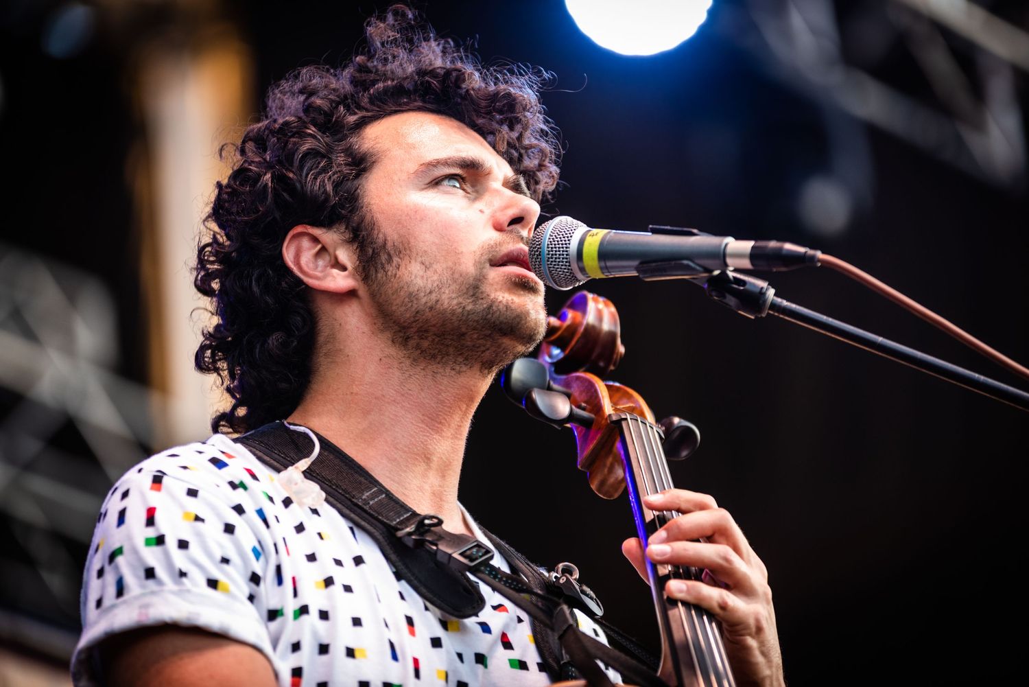 Musician performs on upright bass with microphone during outdoor concert.