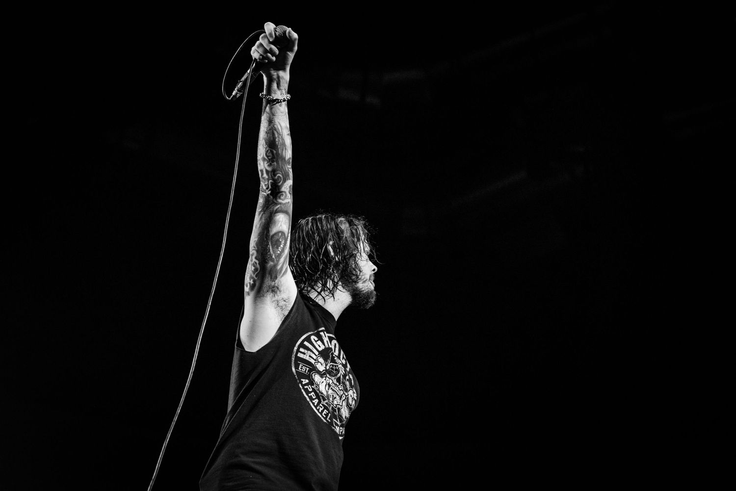 A dramatic black and white shot of a performer with raised arm on stage.
