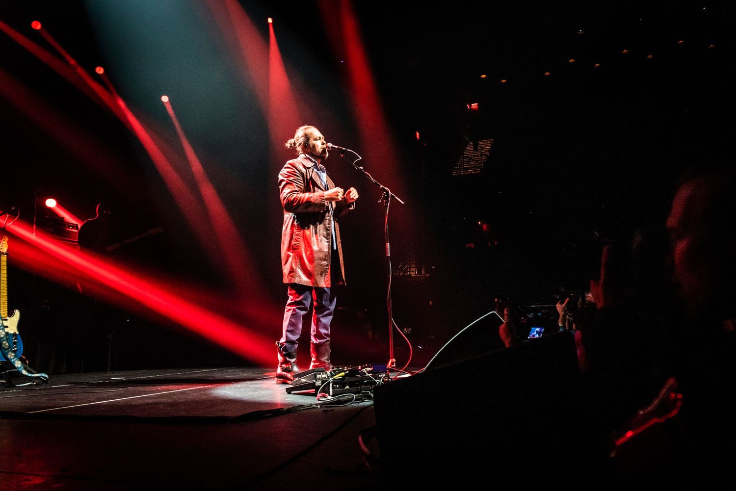 Concert performer on stage bathed in dramatic red lighting during live performance.