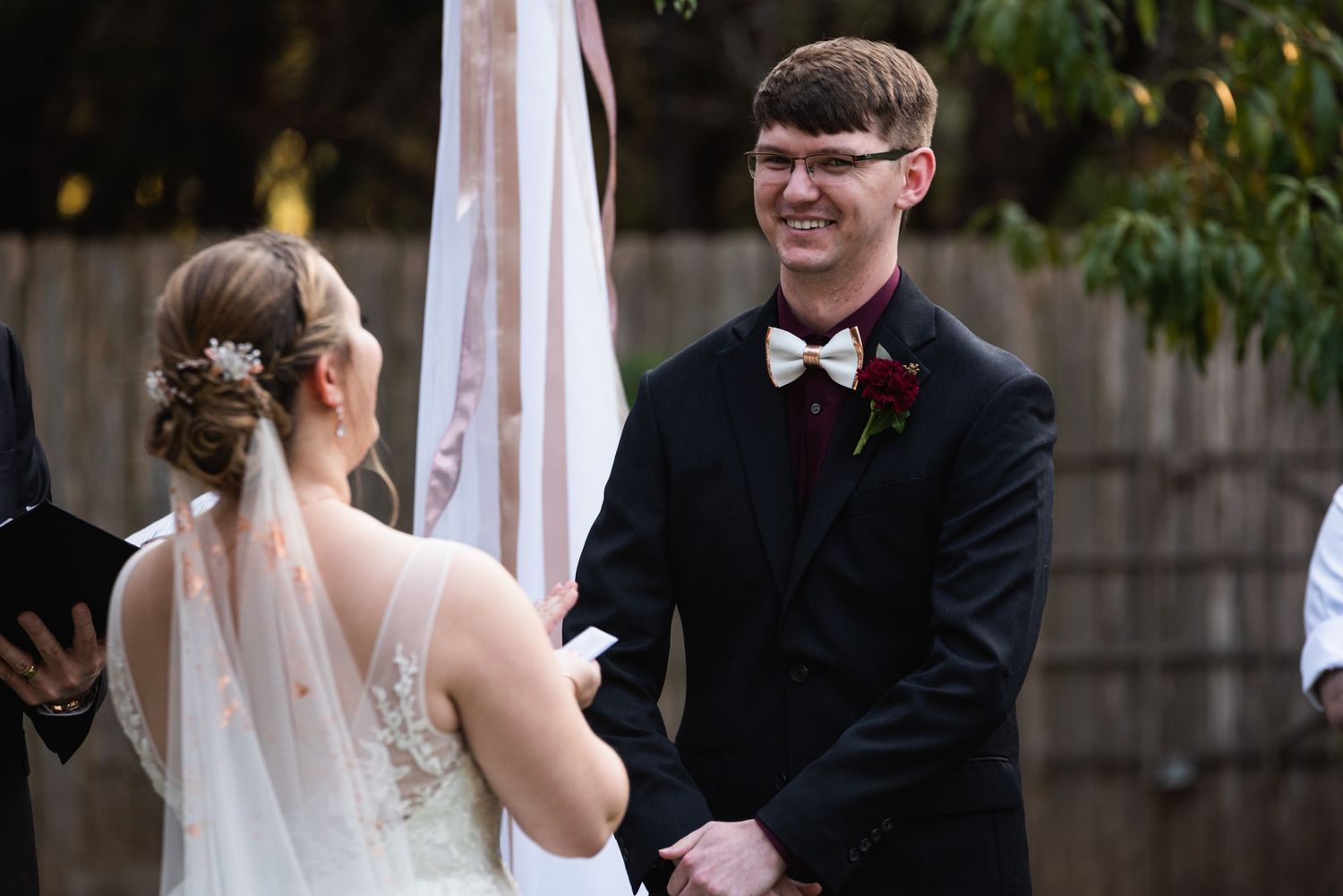 A couple shares a moment during their outdoor wedding ceremony with white decor elements.