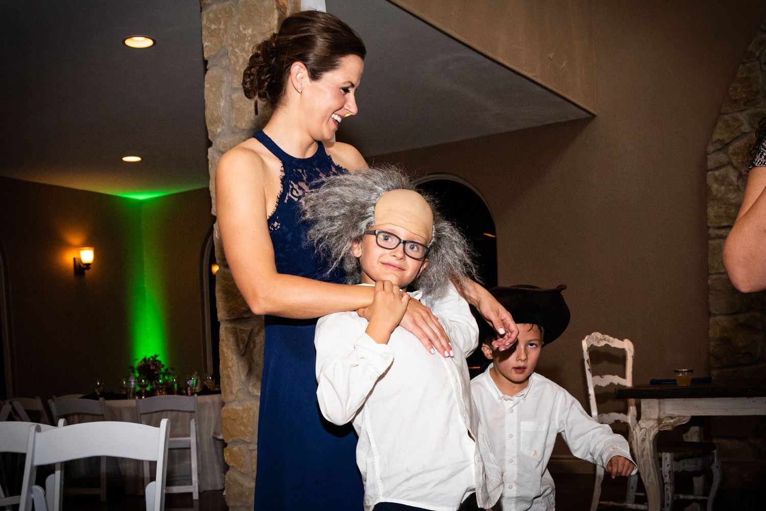 Guests share a tender dancing moment at an elegant wedding reception with green accent lighting.