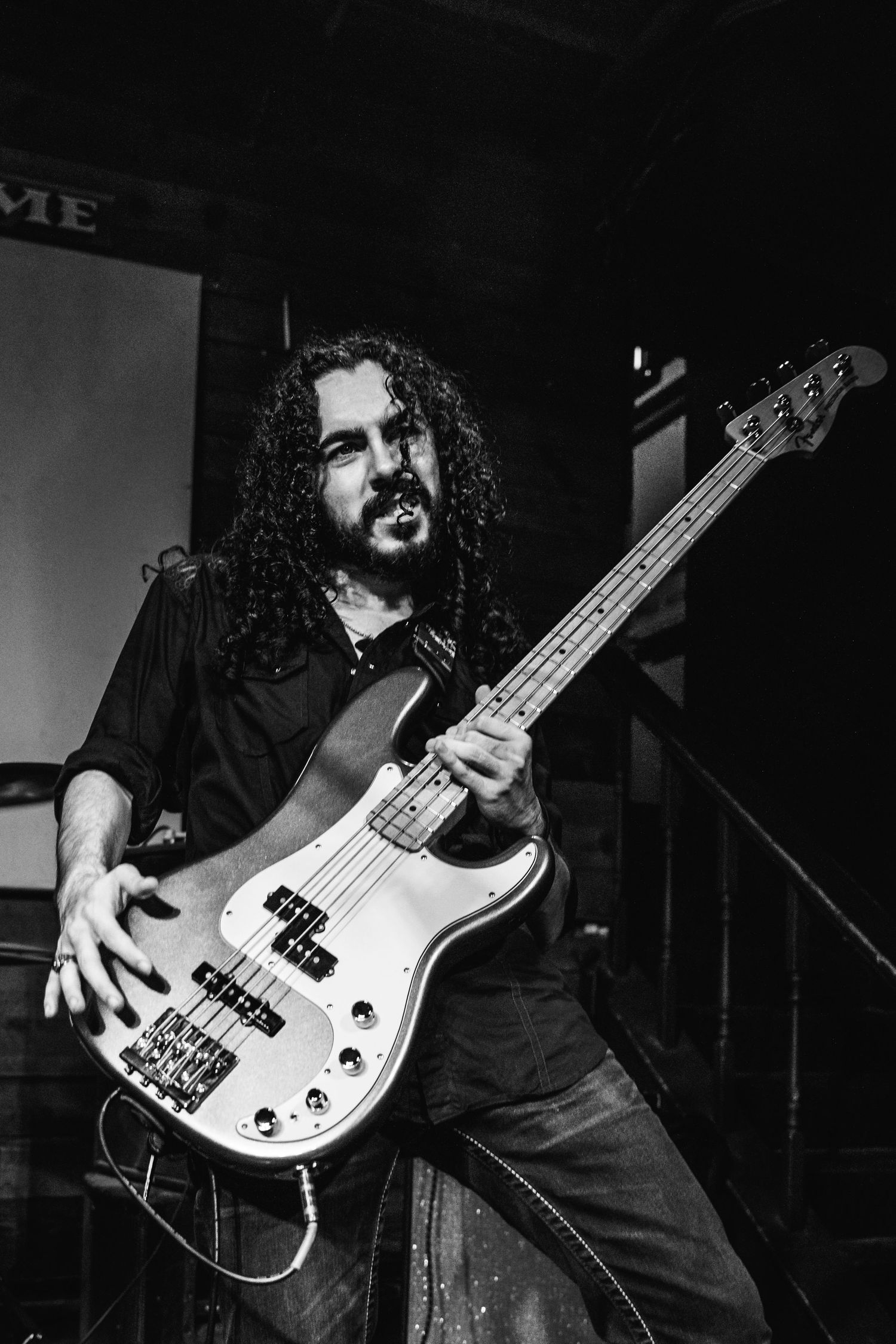 A bass guitarist in dark clothing performs on stage with a white bass guitar in a black and white photo sequence.