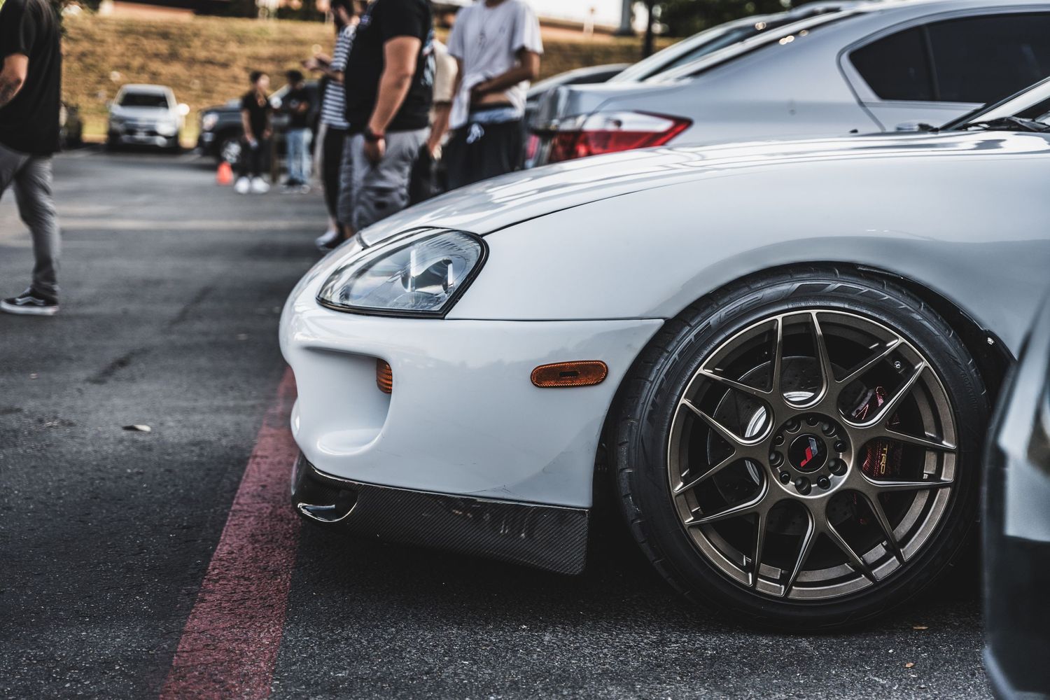 Close-up detail shot of a white Toyota Supra's front quarter panel and aftermarket wheel.