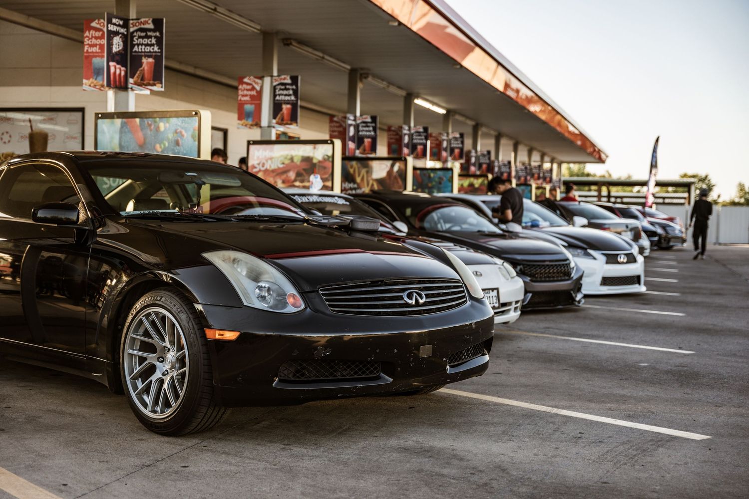 Line of classic Infiniti G35s and other luxury cars parked at automotive meet.