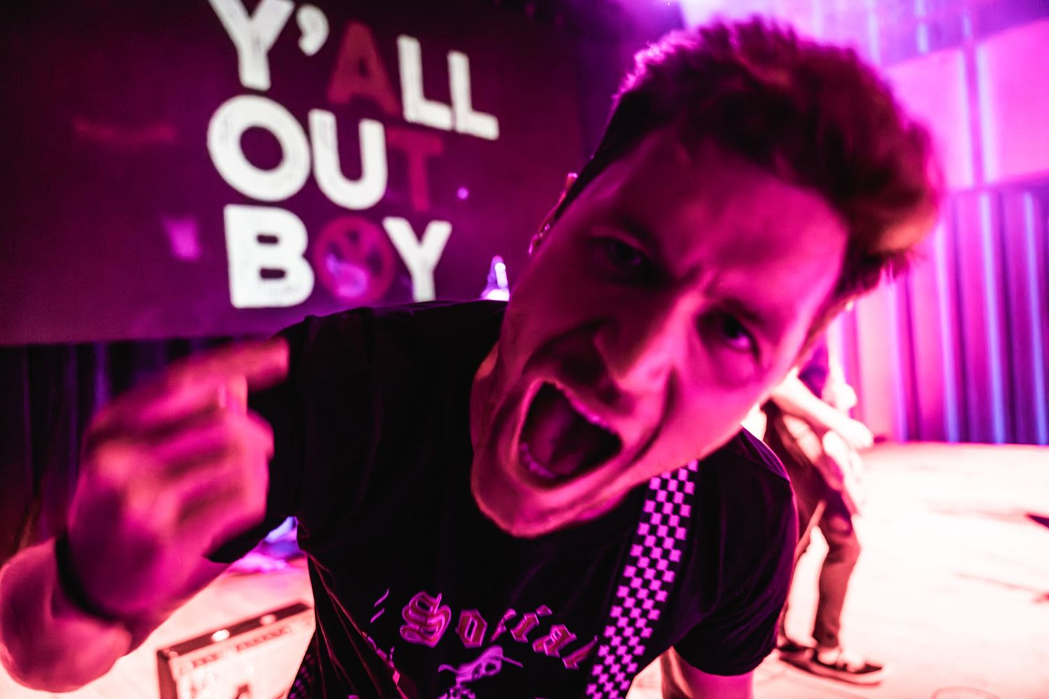 Musician performing with intense expression under magenta stage lighting.