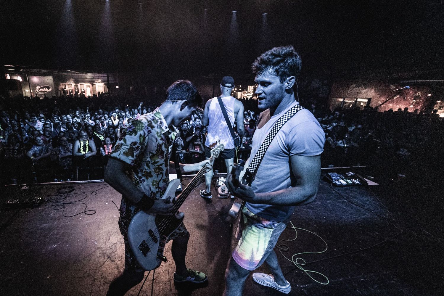 Musicians perform energetically on stage with guitar during live concert.