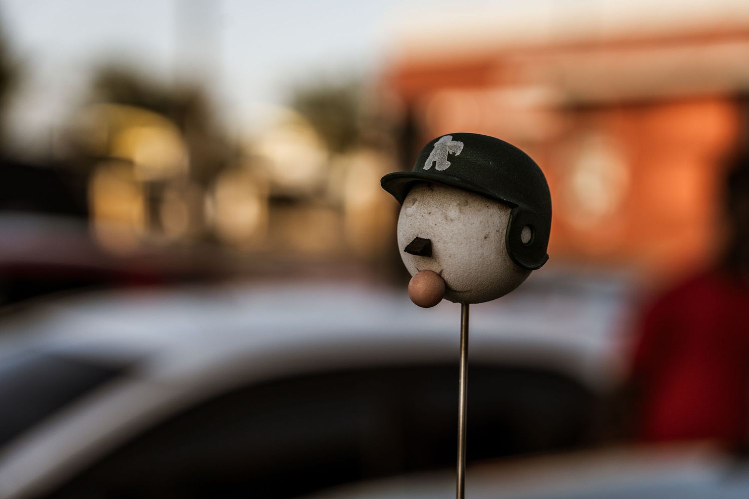 A decorative antenna topper with a black baseball cap displayed on a car.