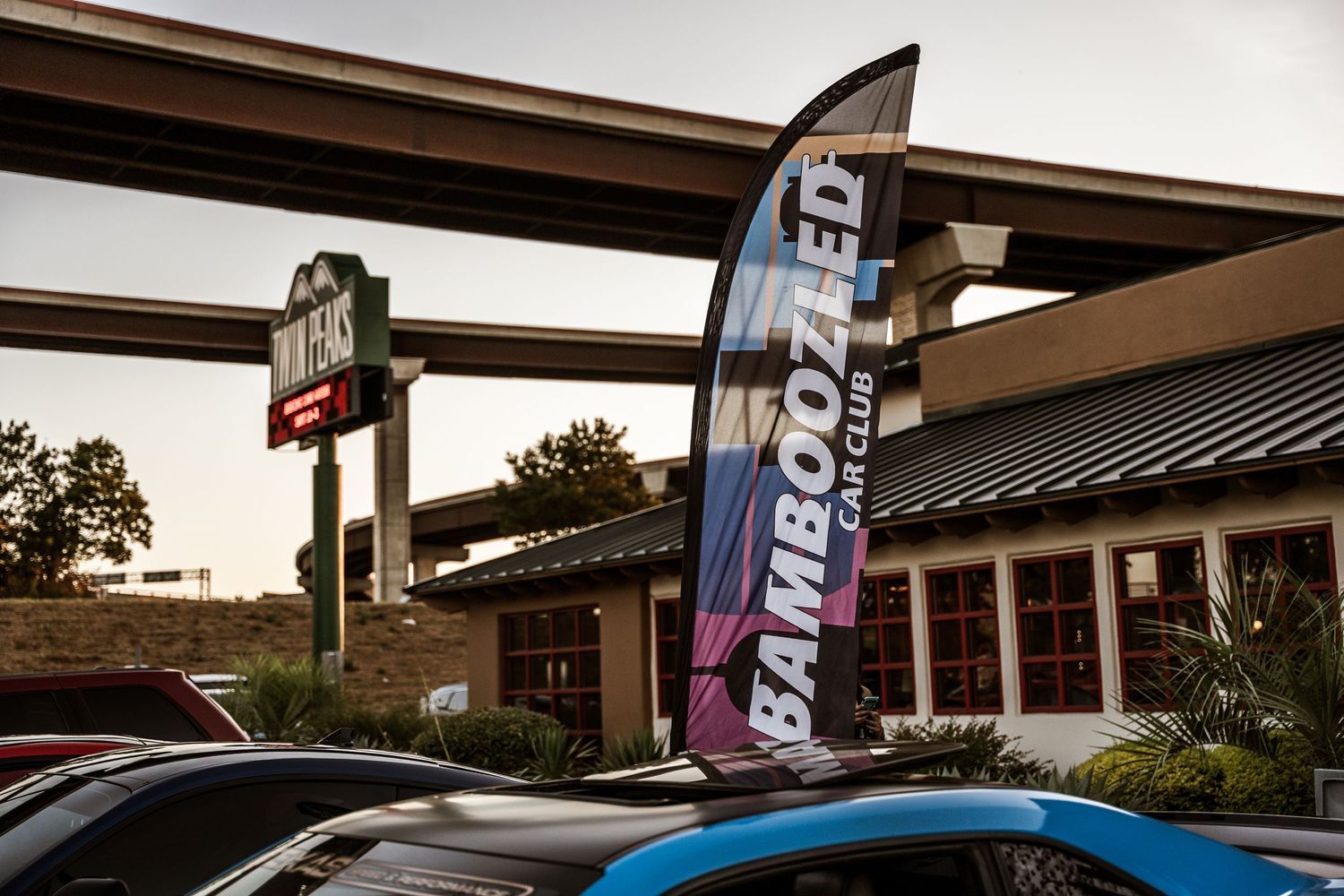 Twin Peaks restaurant exterior with feather flag banner at sunset.