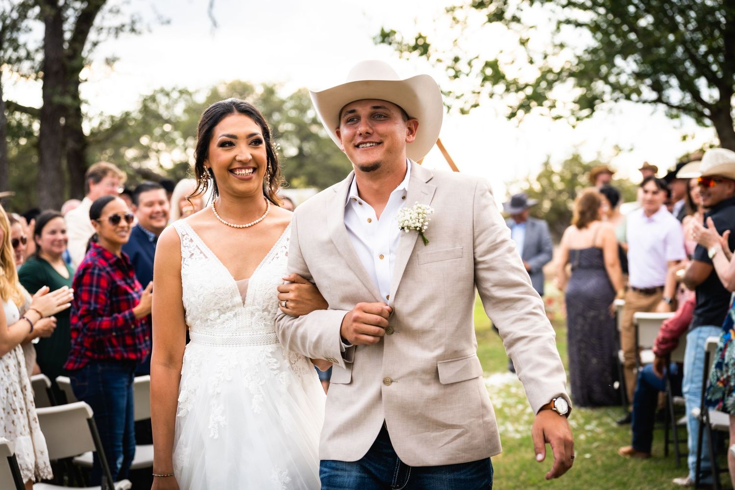 A newly married couple walks down the aisle at their outdoor country wedding.