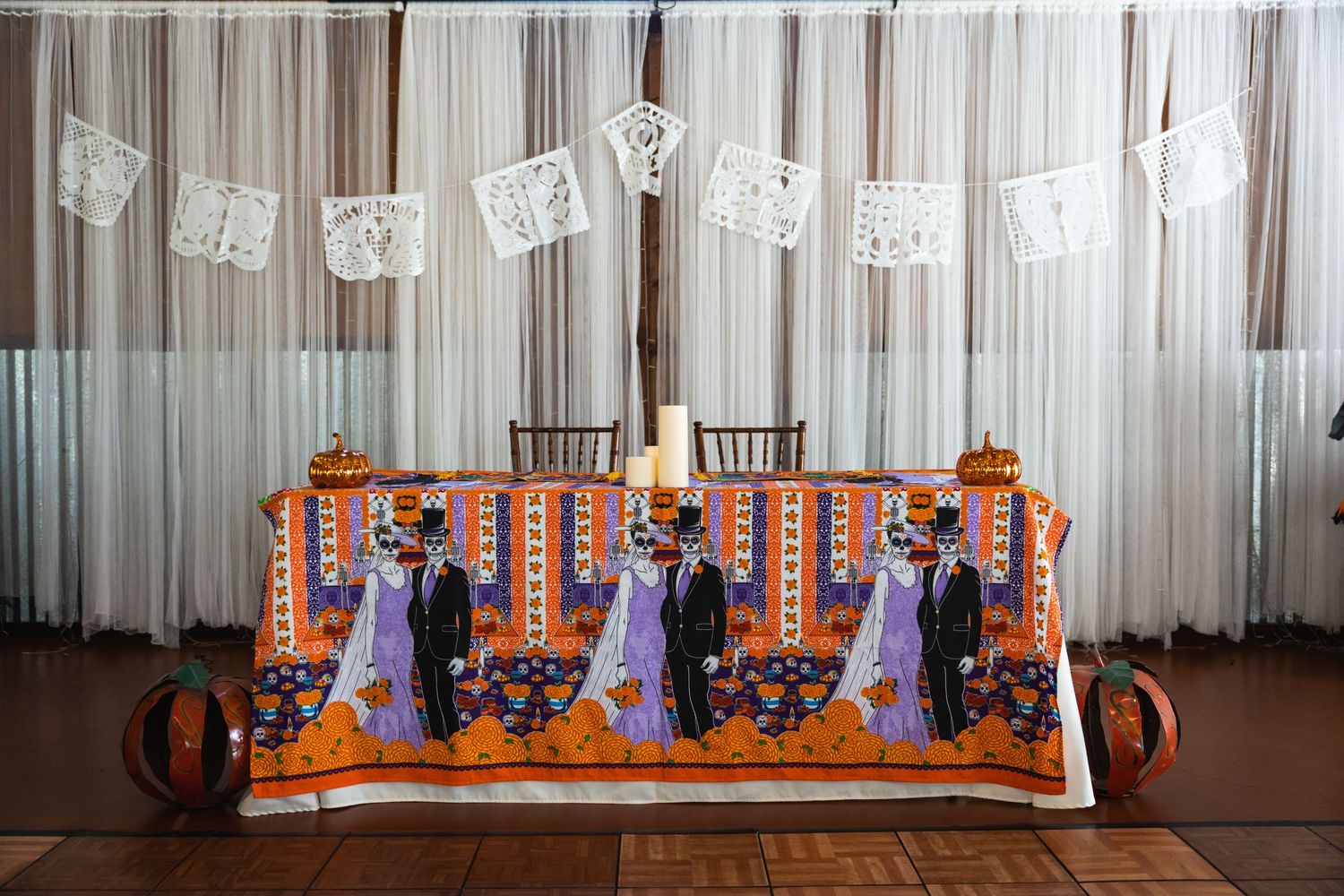Orange and purple themed wedding table display with vintage papel picado banners hanging above.