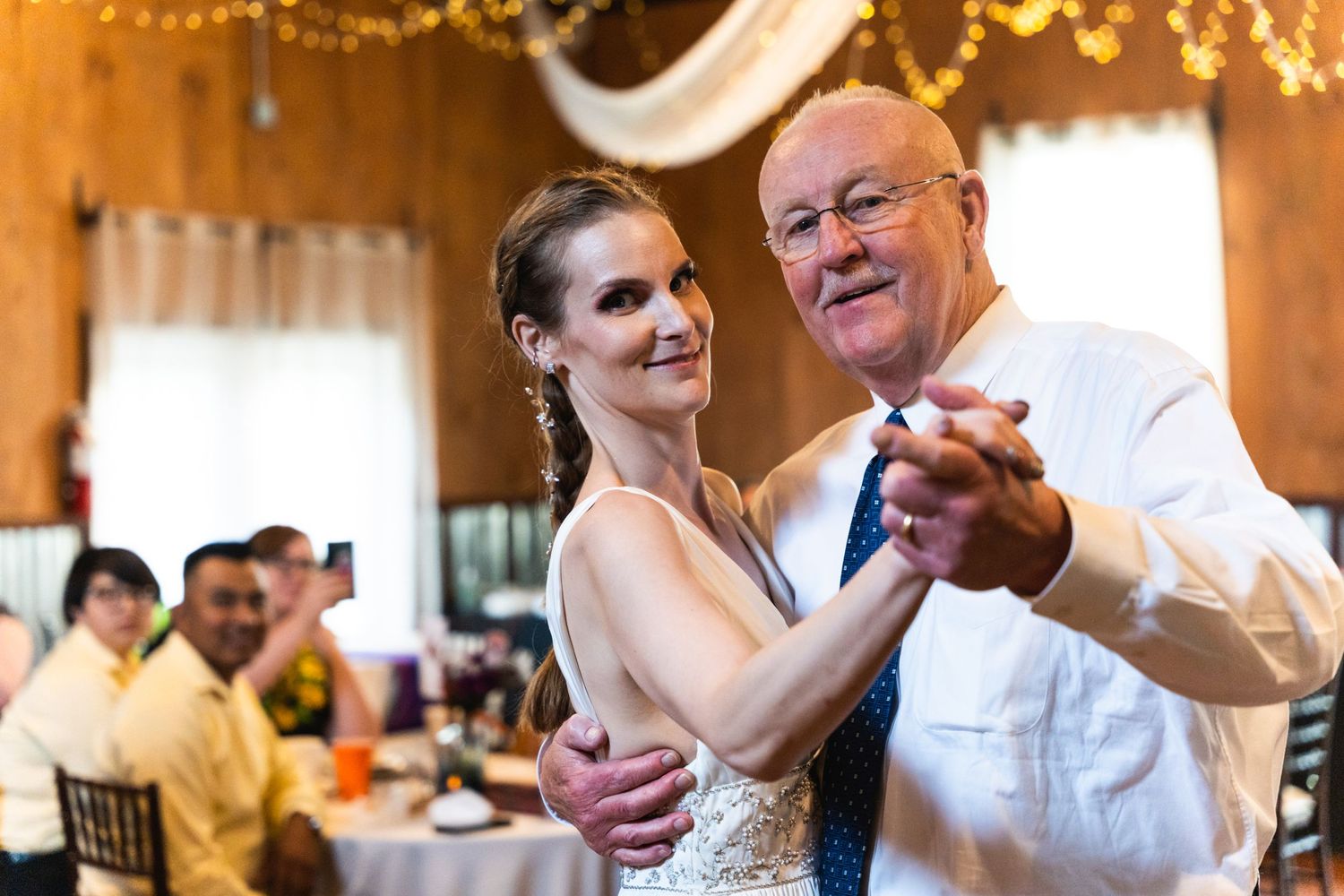 A couple shares a dance together during their wedding reception in a warmly lit venue.