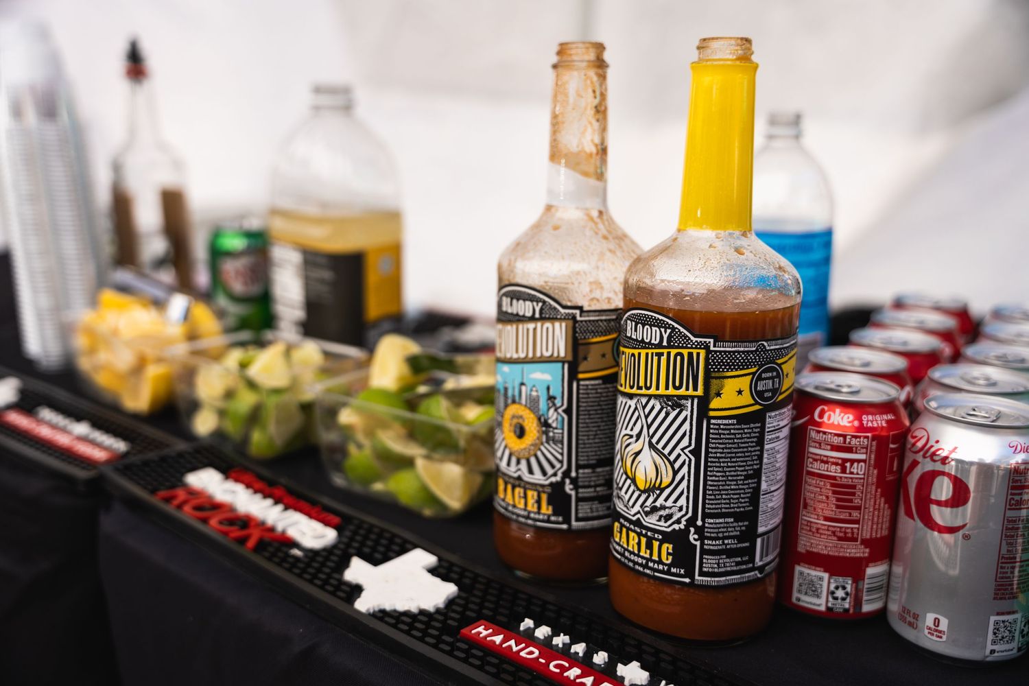 Assorted bottles of alcohol and mixers arranged on a black surface at a party bar setup.