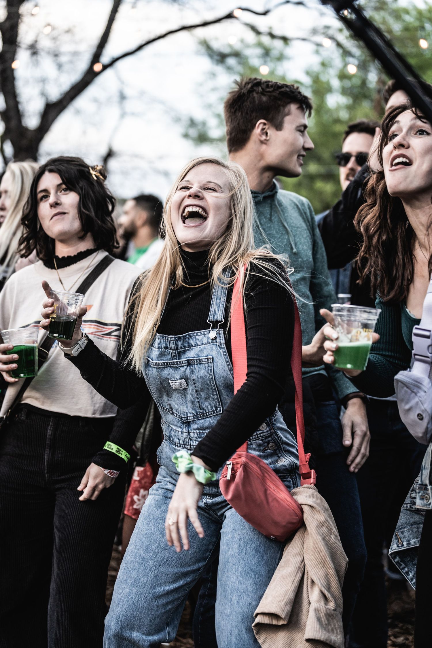 Festival attendees in casual attire laughing and enjoying live entertainment outdoors.