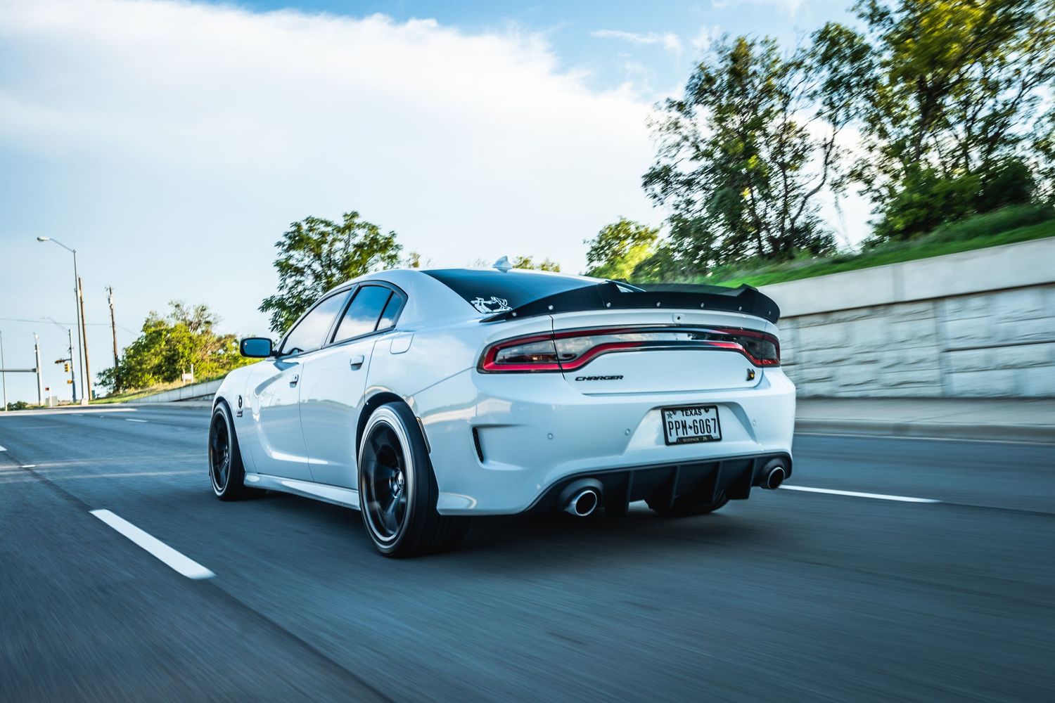 White Dodge Charger with performance modifications captured in dynamic highway shot.