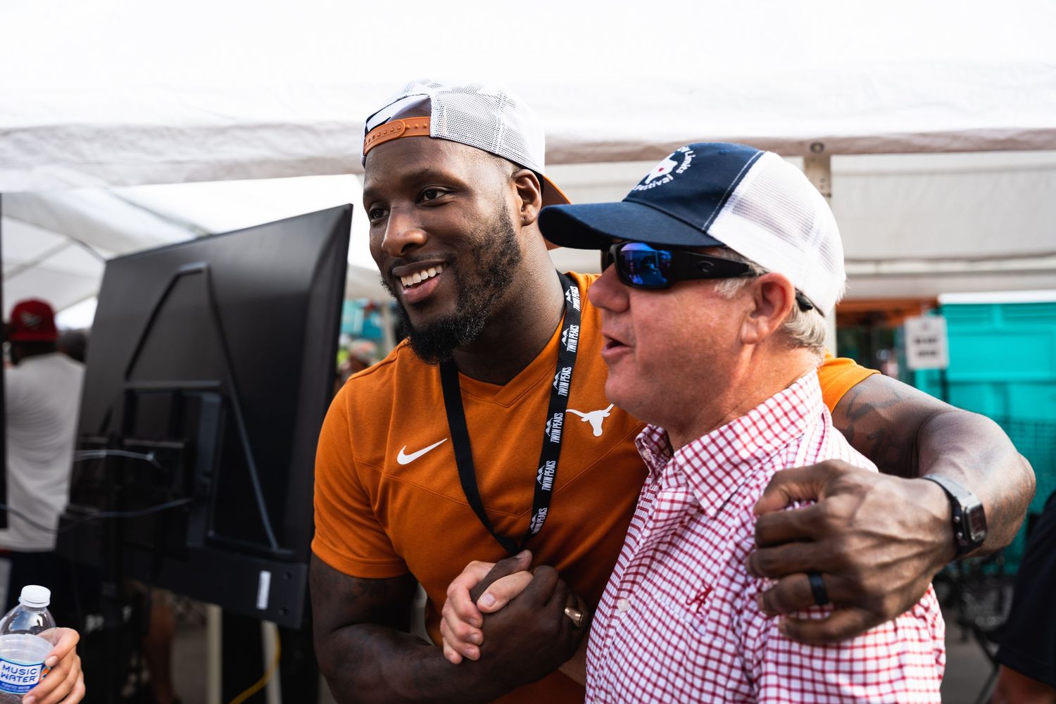 Two people sharing a laugh at an outdoor sporting event.