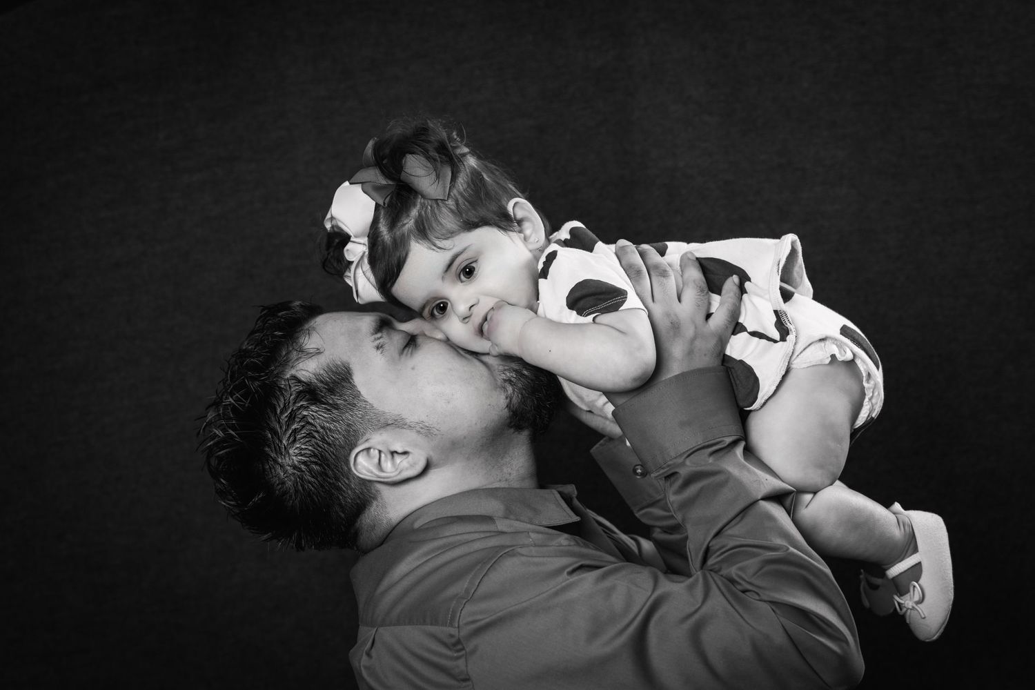 A tender black and white portrait capturing a playful moment between parent and child.