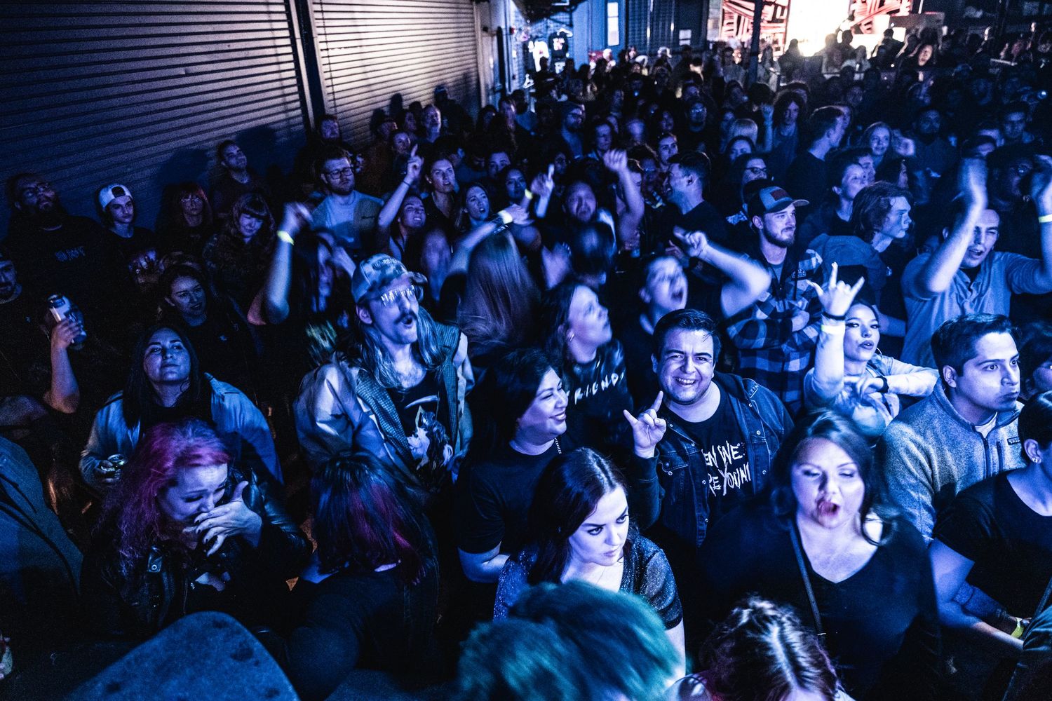 A densely packed concert crowd illuminated by blue stage lighting.