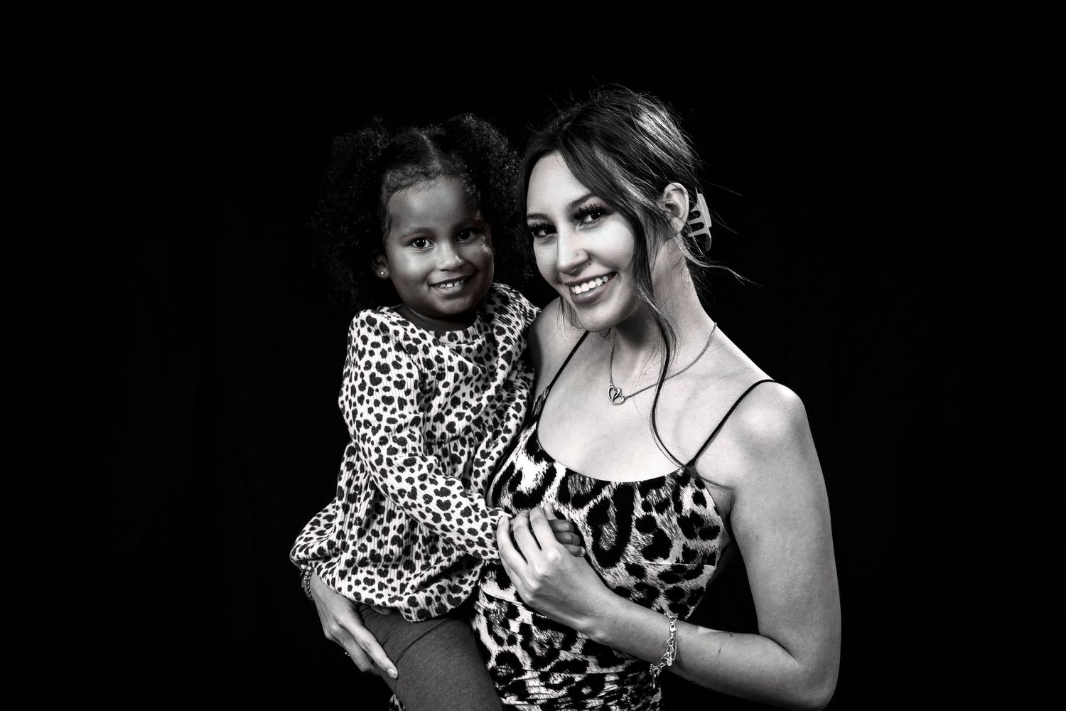 Black and white photo of two people wearing matching animal print clothing.