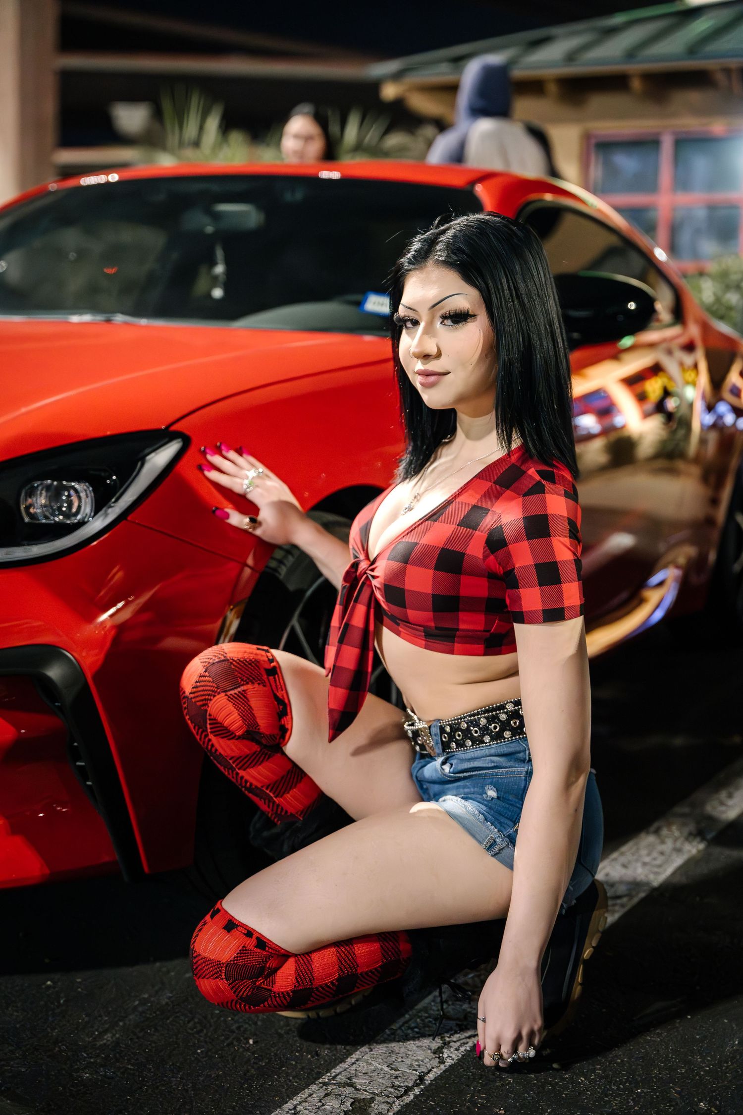 Red sporty hatchback car with custom modifications displayed at night.