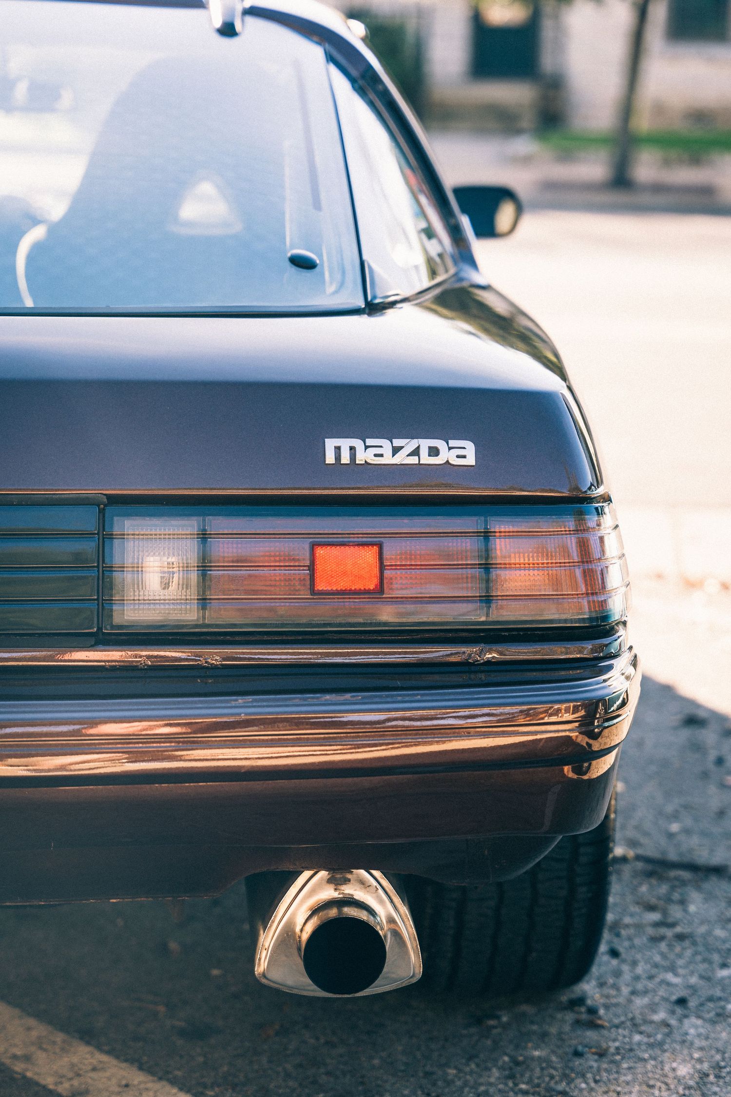 Close-up detail of a classic Mazda's rear end showing taillights and exhaust.