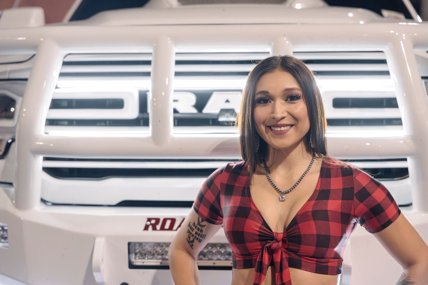 Red plaid crop top shown against white RAM truck grille in automotive photoshoot.