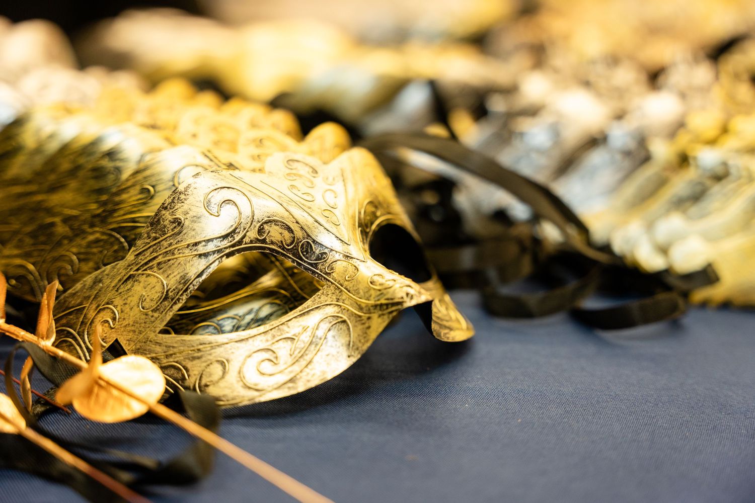 Ornate golden masquerade mask with intricate swirling designs displayed against a dark background.