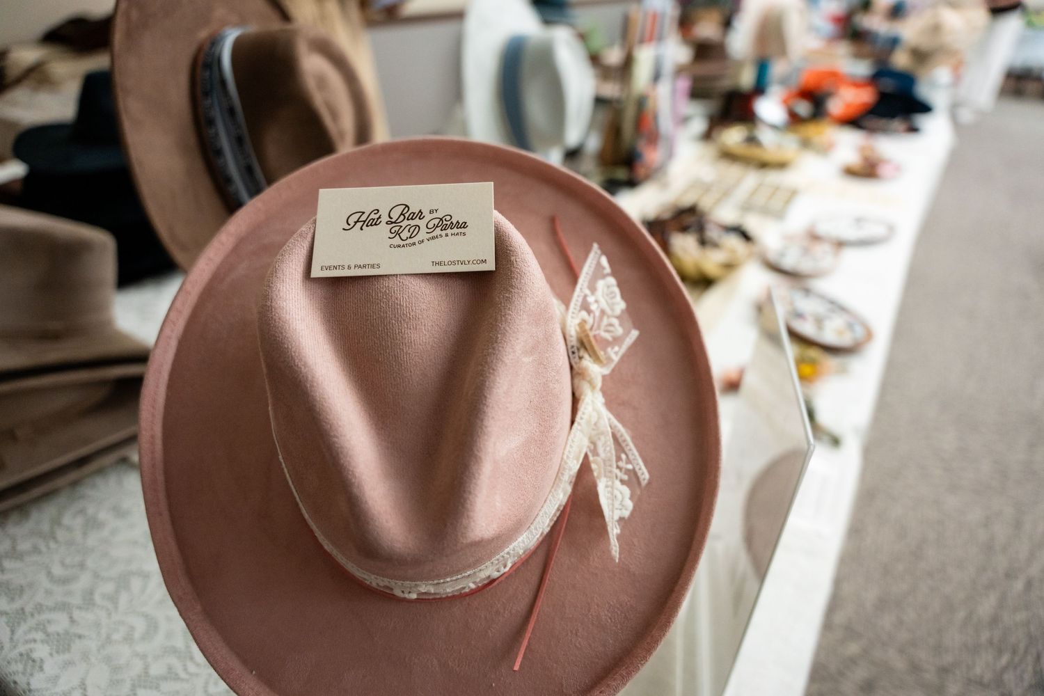 A dusty pink fedora hat with decorative ribbon displayed on a white surface.