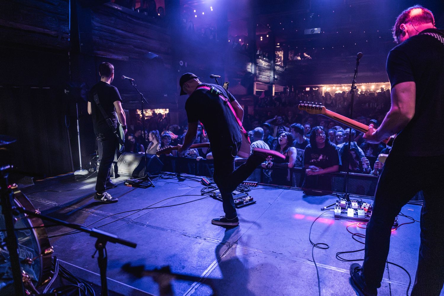 Band performing on stage with dramatic blue lighting at an indoor music venue.