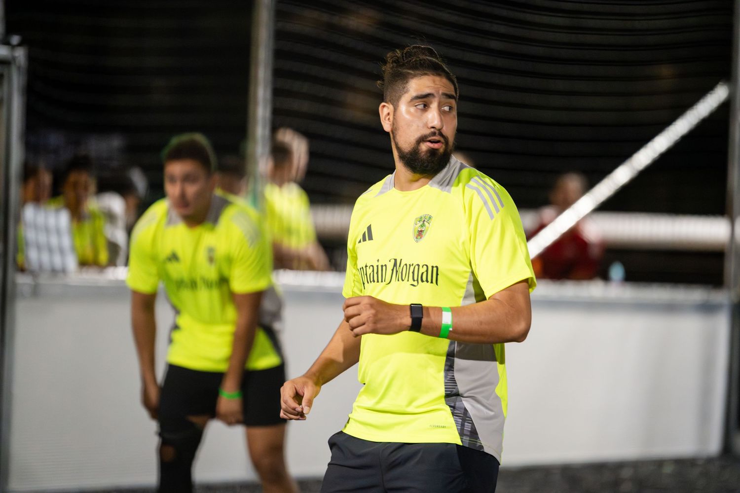 Players in bright yellow jerseys participate in an indoor soccer game.