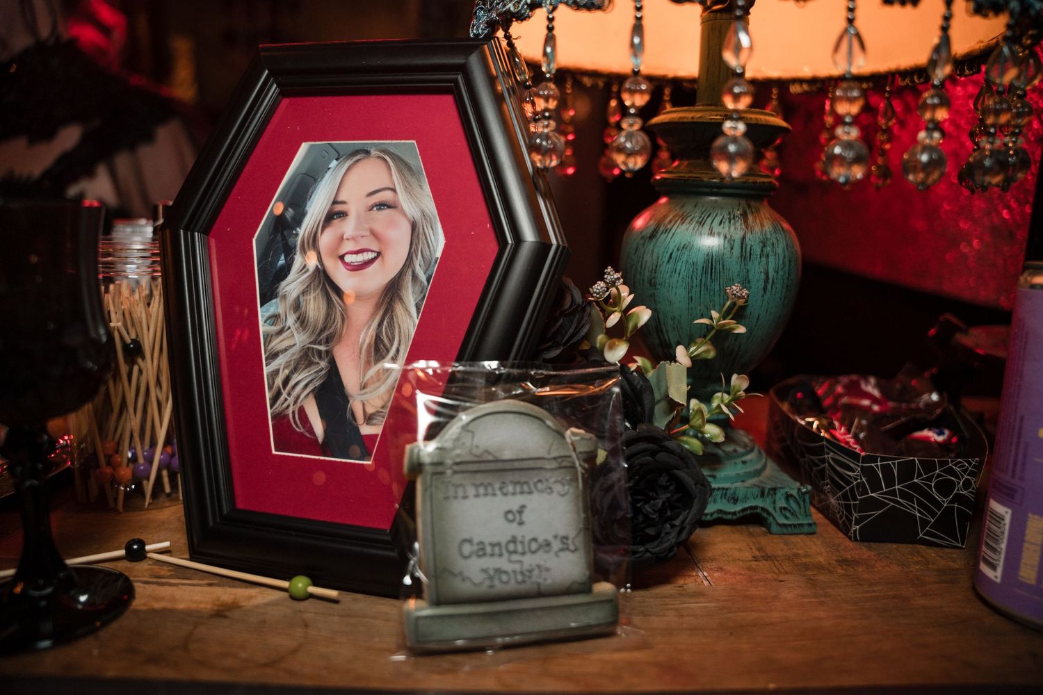 Gothic-style decor arrangement with framed art, teal vase, and decorative items on wooden surface.
